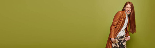 Молодой человек с длинными рыжими волосами выражает свои чувства в яркой, стильной обстановке.