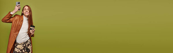 Эмоциональный молодой человек улыбается и позирует для селфи, наслаждаясь кофе в художественной атмосфере.