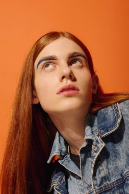 Parlak kızıl saçlı genç adam koyu turuncu bir arka plana karşı derin duygular gösteriyor..