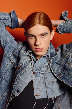 Uzun kızıl saçlı genç adam, çarpıcı bir şekilde poz verirken derin duygular ifade eder..