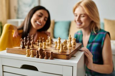 İki kadın, oturma odalarında satranç oynarken aynı kahkahayı ve aşkı paylaşıyor..