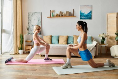 İki kadın, parlak ve davetkar bir oturma odasında yoga minderleri üzerinde şakalaşarak egzersiz yapıyorlar..