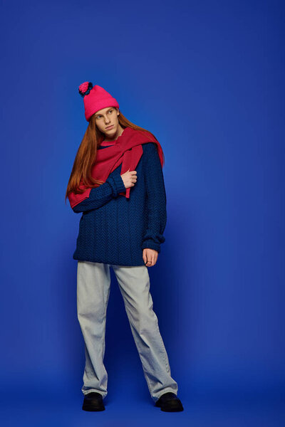 Молодой человек с длинными рыжими волосами демонстрирует свои эмоции в яркой зимней одежде.