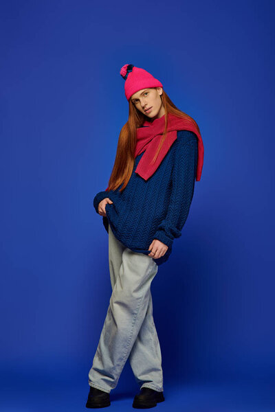 A young man with long red hair showcases emotions while dressed in cozy attire.