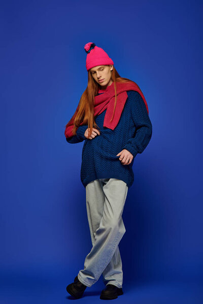 Молодой человек с яркими рыжими волосами демонстрирует глубокие эмоции во время ношения уютного зимнего платья.