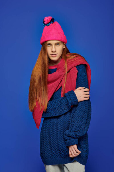 A young man expresses deep emotions while dressed in warm clothing, featuring striking red hair.