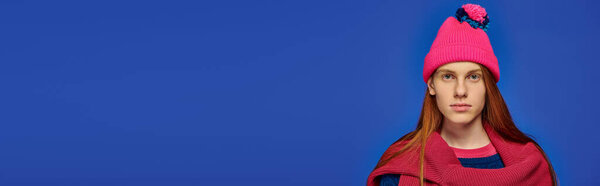 Young man with long red hair expresses deep emotions while wearing a colorful knit hat.