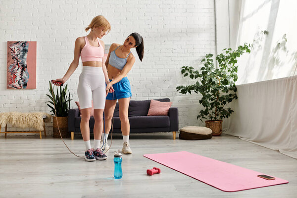 Two young women share fitness tips while exercising together in their bright living room.