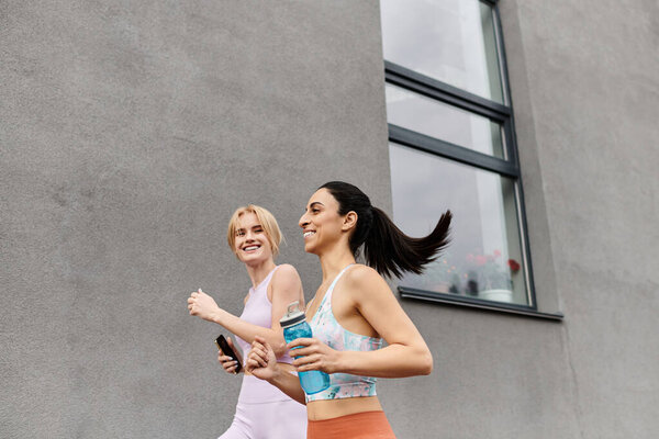 Two young women share laughter while jogging together in a vibrant urban setting.