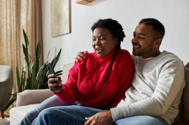 Mutlu bir çift sıcak bir kanepede, sıcak kazaklara sarılı ve kahkahalarla kaliteli vakit geçirmeyi sever..