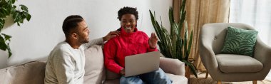 Loving couple shares joyful laughter at home while wearing cozy sweaters during winter. clipart