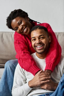 A happy couple enjoys quality time together in cozy sweaters, celebrating winter indoors. clipart