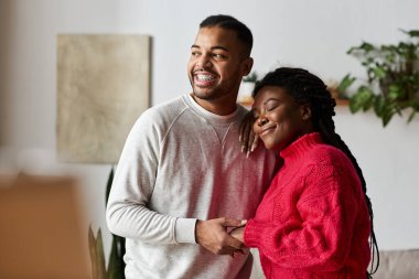 Sıcak süveter giyen mutlu bir çift evde dinlenirken sevgi dolu bakışlar atar..