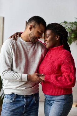 A joyful couple embraces each other in warm sweaters, enjoying quality time together at home. clipart