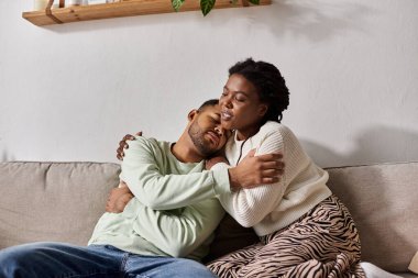 African American couple wearing cozy sweaters during winter, woman comforting her sad man clipart