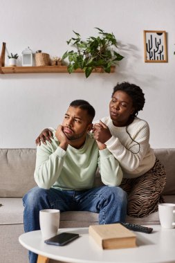 African American couple wearing cozy sweaters during winter, woman comforting her sad partner clipart