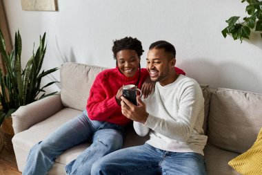 A happy couple enjoys each others company while relaxing together on a cozy sofa. clipart