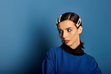 Modaya uygun genç bir kadın stüdyo ortamında poz verirken moda kıyafetlerini sergiliyor..