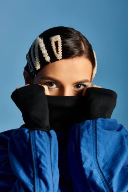 Çekici genç kadın, stüdyo ortamında şık saç tokalarıyla moda kıyafetler sergiliyor..