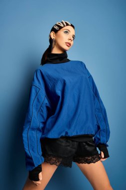 Şık bir genç kadın yaratıcı stüdyo ortamında saç tokalarıyla moda kıyafetler sergiliyor..