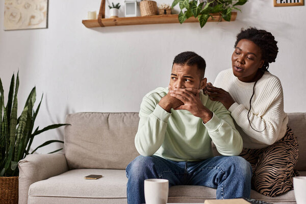 African American couple wearing sweaters during winter, woman comforting her worried partner