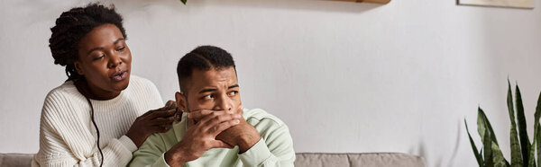 African American couple wearing cozy sweaters during winter, woman comforting her worried partner