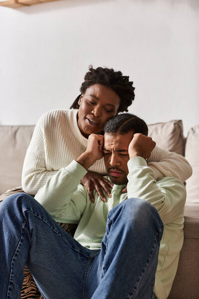 African American couple wearing warm sweaters during winter, woman comforting her sad partner