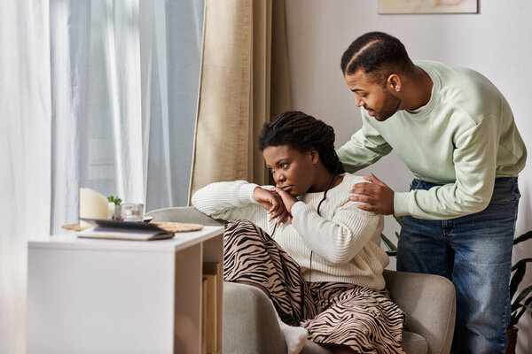 African American man comforting his sad girlfriend in their cozy living room