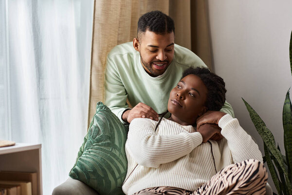 African American man comforting his worried girlfriend in their living room