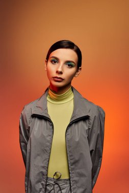 Güzel genç bir kadın, stüdyoda kendine güvenen şık bir kıyafetle poz verir..