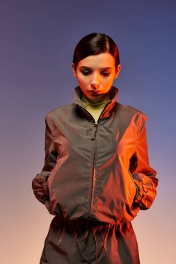 Genç bir kadın, hareketli bir stüdyo arkaplanına karşı modaya uygun kıyafetiyle hava atıyor..