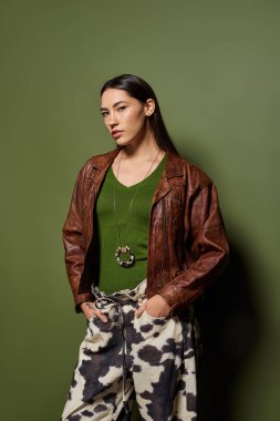 Deri ceket giyen ve sanatsal bir ortamda modern kıyafetler giyen güzel bir esmer.