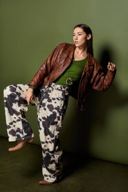 Esmer kadın, modern moda eğilimleri ve zarafeti somutlaştıran şık bir kıyafetin içinde özgüvenle poz veriyor..