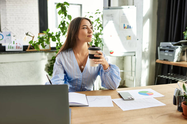 Красивая брюнетка вдумчиво размышляет с кофе, анализируя графики и данные за своим столом.