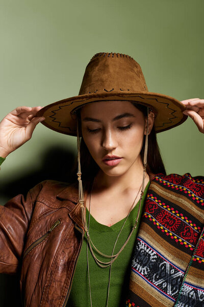 Young beautiful brunette wearing a unique hat and ethnic shawl, exuding calmness and charm.