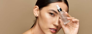 Şık bir genç kadın zarif bir ortamda cilt serumuyla güzellik rutinini geliştirir..