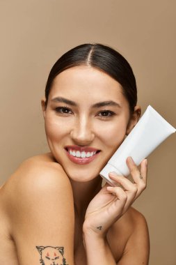 Beautiful brunette woman shows glowing skin while promoting a skincare product in soft light clipart