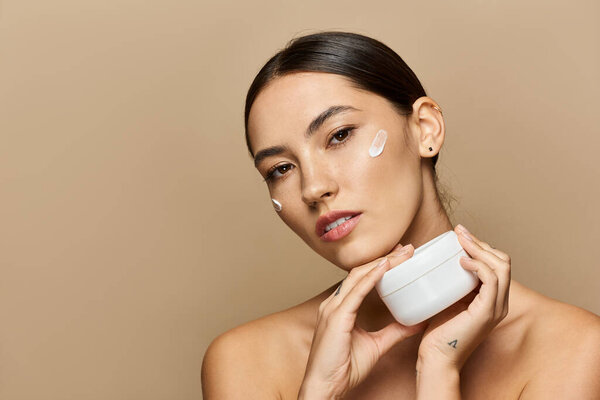 Брюнетка наносит крем вдумчиво, подчеркивая свою сияющую кожу в спокойной обстановке.