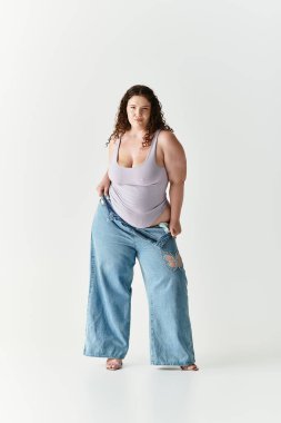 Şık bir genç kadın minimalist stüdyo ortamında kendinden emin bir şekilde büyük beden giyip poz verir.