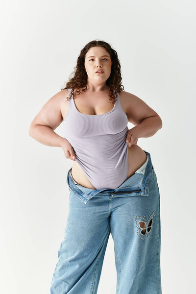 Young woman in a fitted top and oversized jeans radiates confidence and joy.