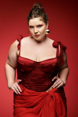 Kendine güvenen, şık kırmızı elbiseli genç bir kadın, kendine has moda anlayışını ön plana çıkarıyor..