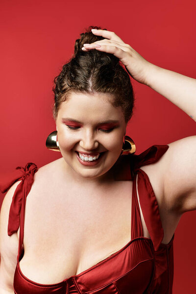 A stylish woman in a chic red outfit joyfully poses for the camera, radiating confidence.