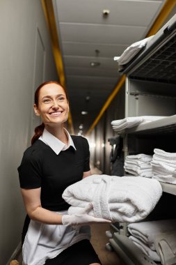 Bright hallway features a young woman happily organizing fresh towels with care. clipart