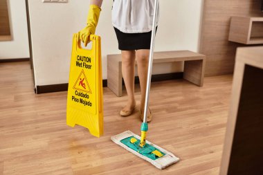 A beautiful young woman mops the floor with care, displaying her dedication to cleanliness. clipart