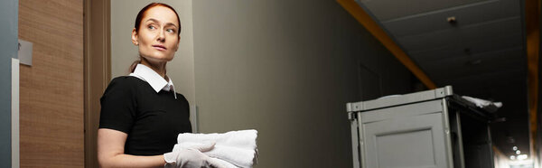 A beautiful young woman holds neatly folded towels, ready to serve guests at a hotel.