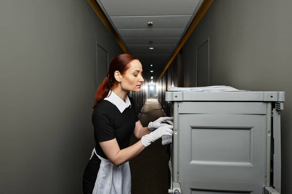 In a modern hallway, a young woman organizes her surroundings with grace and determination.