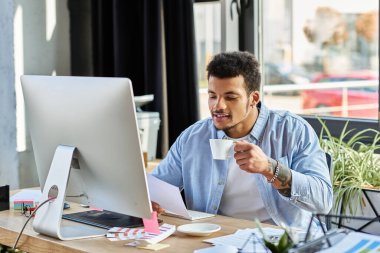 Bu çekici adam, görevlerini yaparken modern, yeşil çalışma alanında kahvesini yudumluyor..