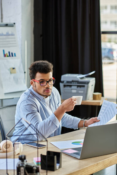 Focused individual sips coffee and analyzes reports in a contemporary workspace filled with light