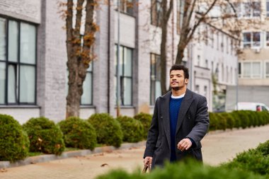 Şık bir adam güvenli bir şekilde ağaçlık yolda yürüyor, gevrek havanın tadını çıkarıyor..