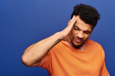 Handsome man expresses strong feelings while standing in front of a striking blue wall clipart